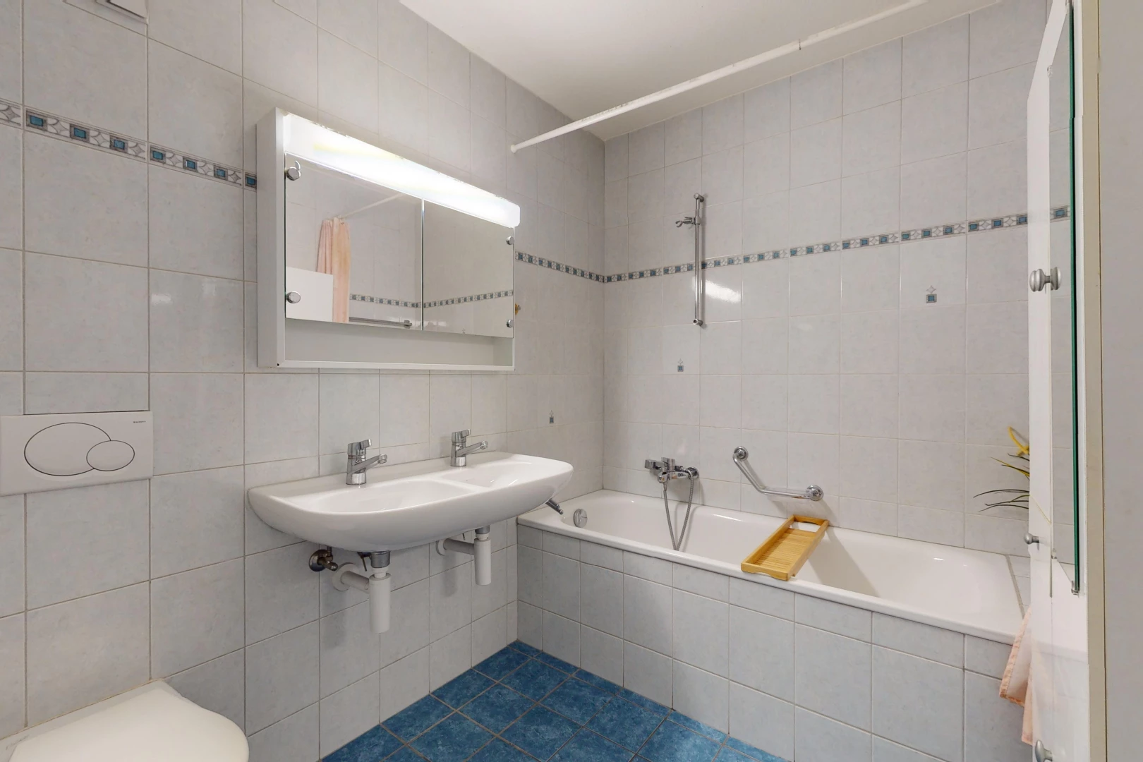 salle de bain avec vasque, miroir, bain-douche, mur carrelé, et toilettes