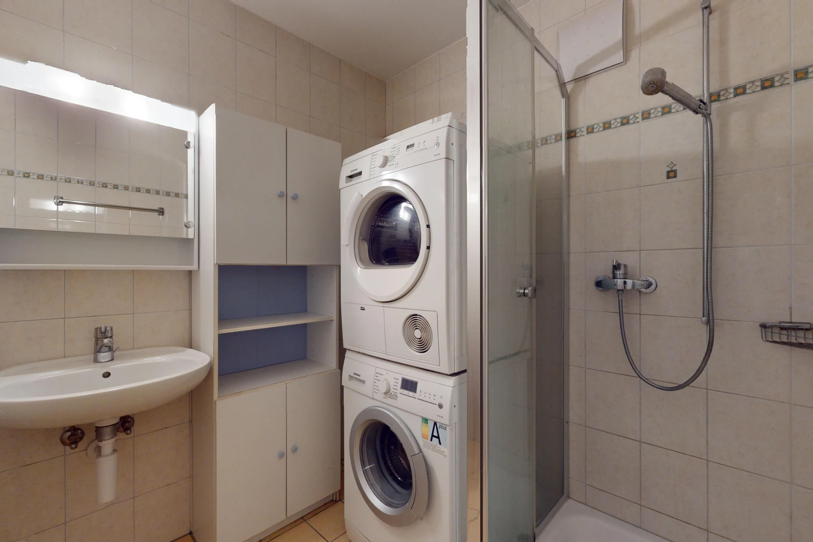 buanderie avec carrelage, buanderie, mur carrelé, et machine à laver / sèche-linge superposés