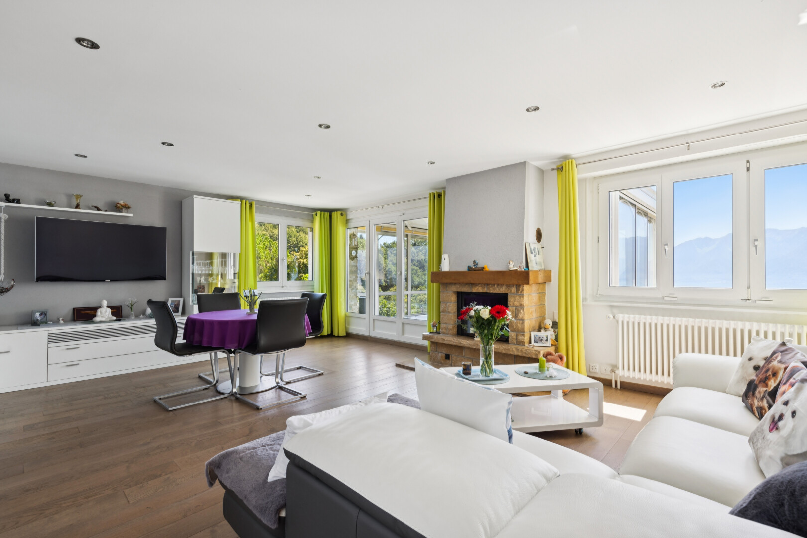 salon avec radiateur, télévision, éclairage encastré, lumière naturelle, et sol en finition bois