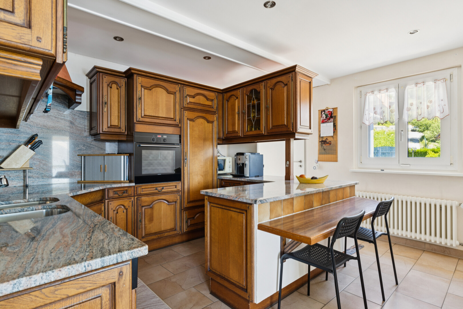 cuisine avec armoires en arc, arched cabinets, armoires avec insert en verre, glass insert cabinets, et plans de travail en pierre