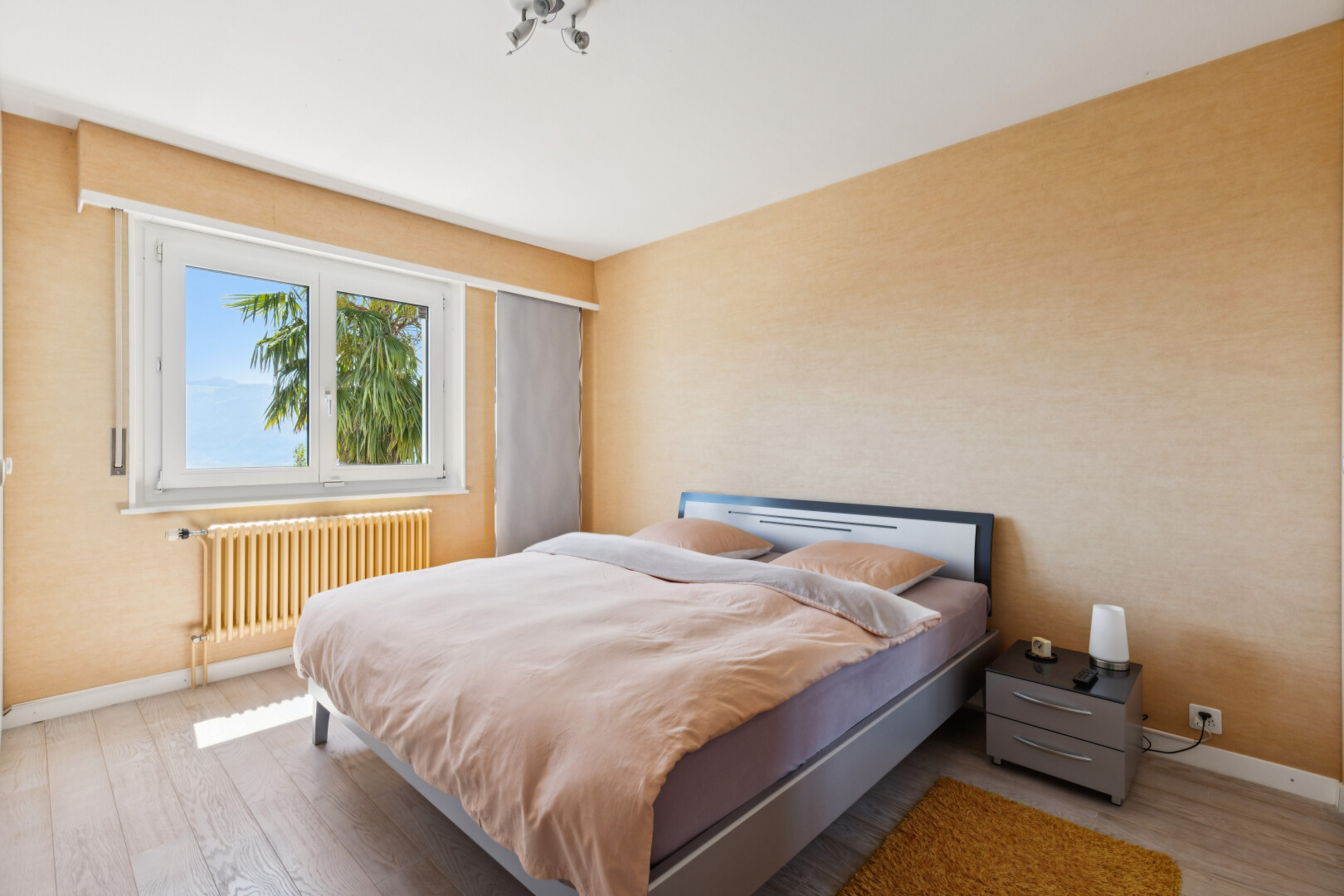 chambre avec radiateur, sol en finition bois, wood finish floor, plinthes murales, et baseboards wall