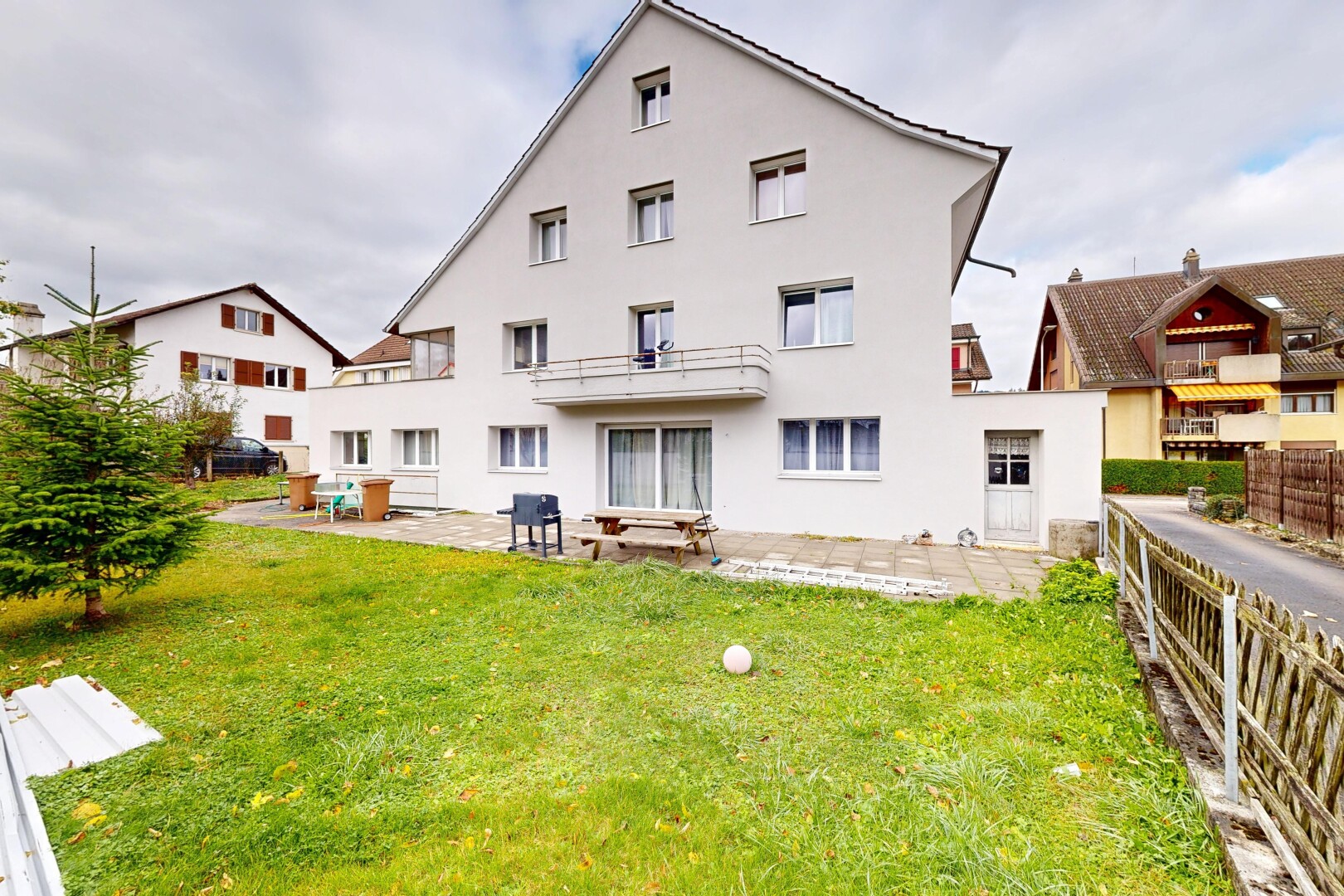 façade avec terrasse, bardage en stuc, et pelouse