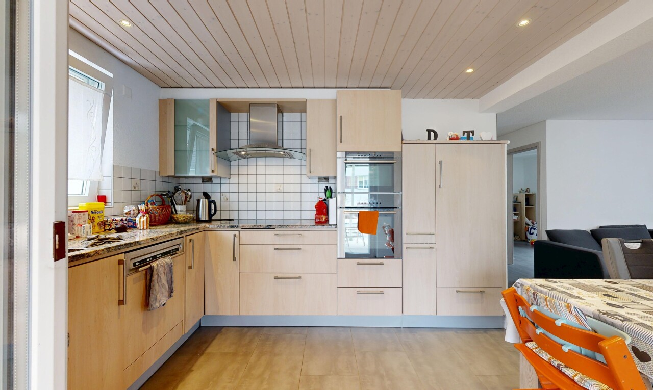 cuisine avec plafond en bois, wood ceiling, hotte, four double, et armoires marron clair