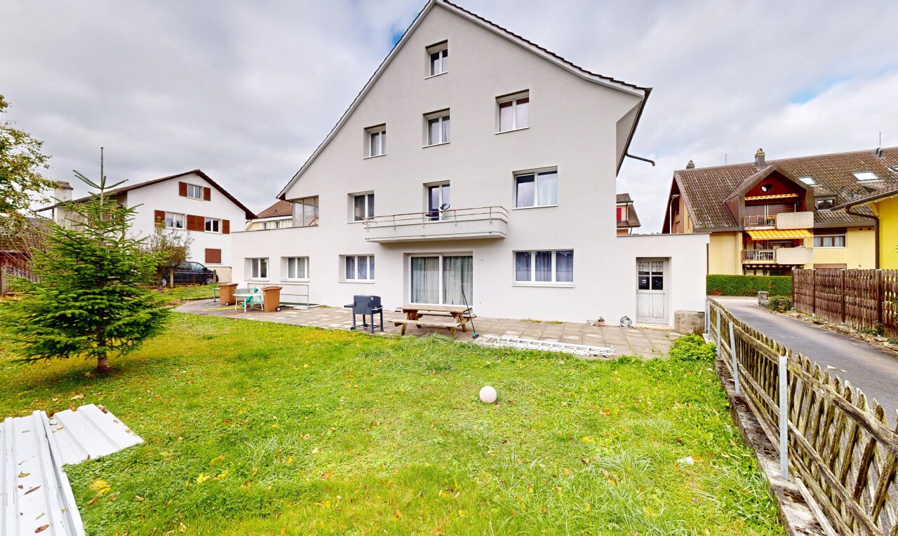 façade avec terrasse, bardage en stuc, et pelouse