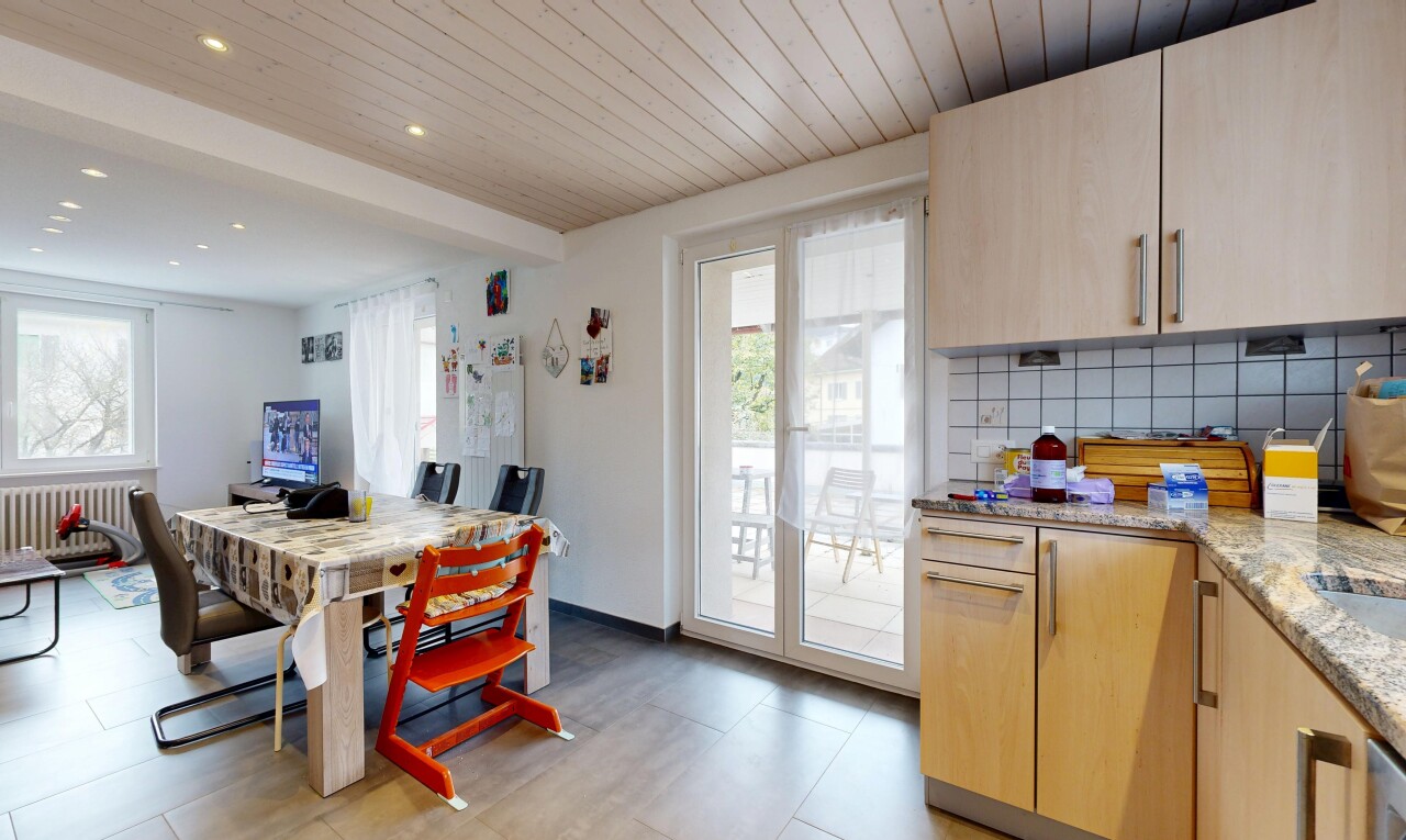 cuisine avec armoires marron clair, plafond en bois, wood ceiling, plans de travail en pierre, et lumière naturelle