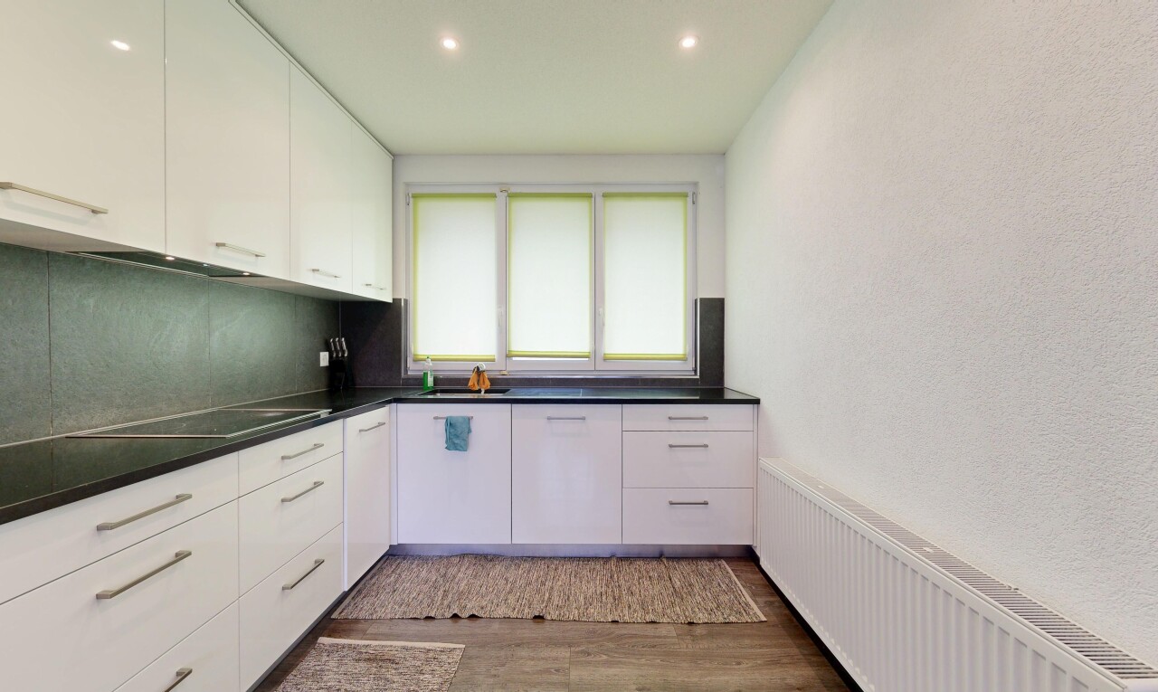 cuisine avec armoires blanches, radiateur, plans de travail, wood finish floor, et inside property