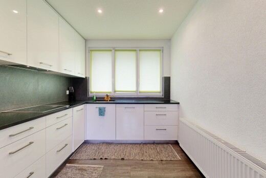cuisine avec armoires blanches, radiateur, plans de travail, wood finish floor, et inside property