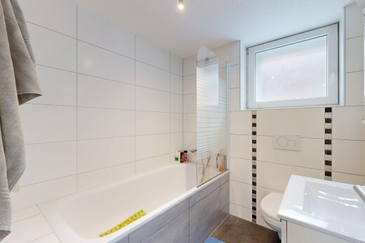 bathroom with vanity, tiled tub, and tile walls