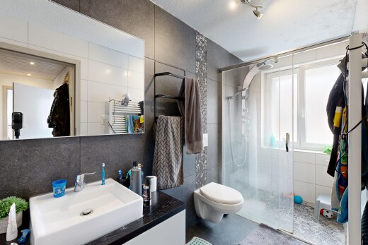 full bath with tile walls, a stall shower, vanity, and a towel warmer