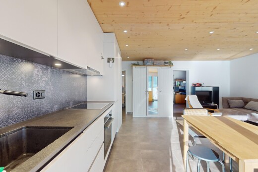 küche mit herd, küchenrückwand beim herd, weiße schränke, und öffnet sich zum wohnraum