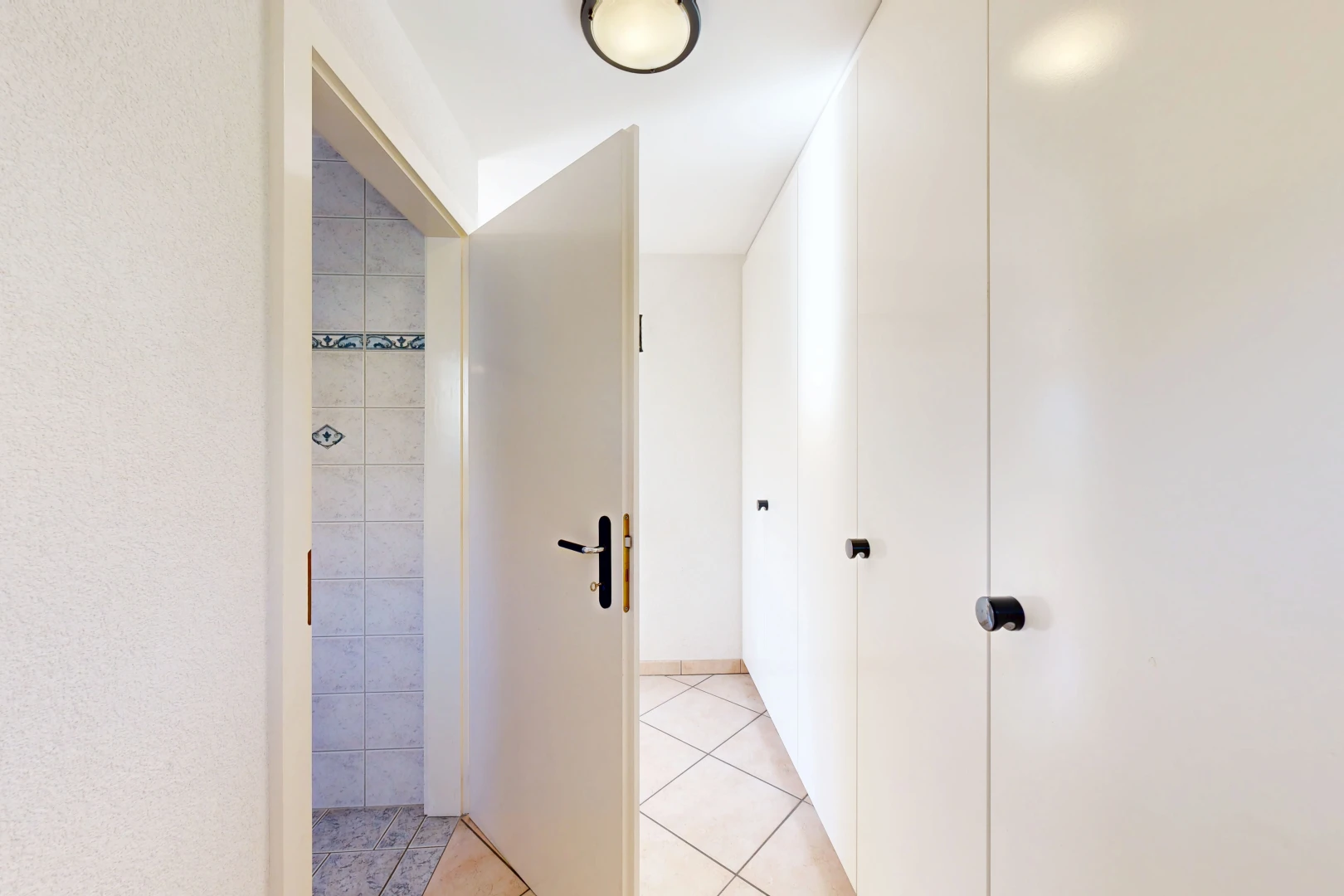 couloir avec light floor, tile floor, sol en carrelage, et inside property