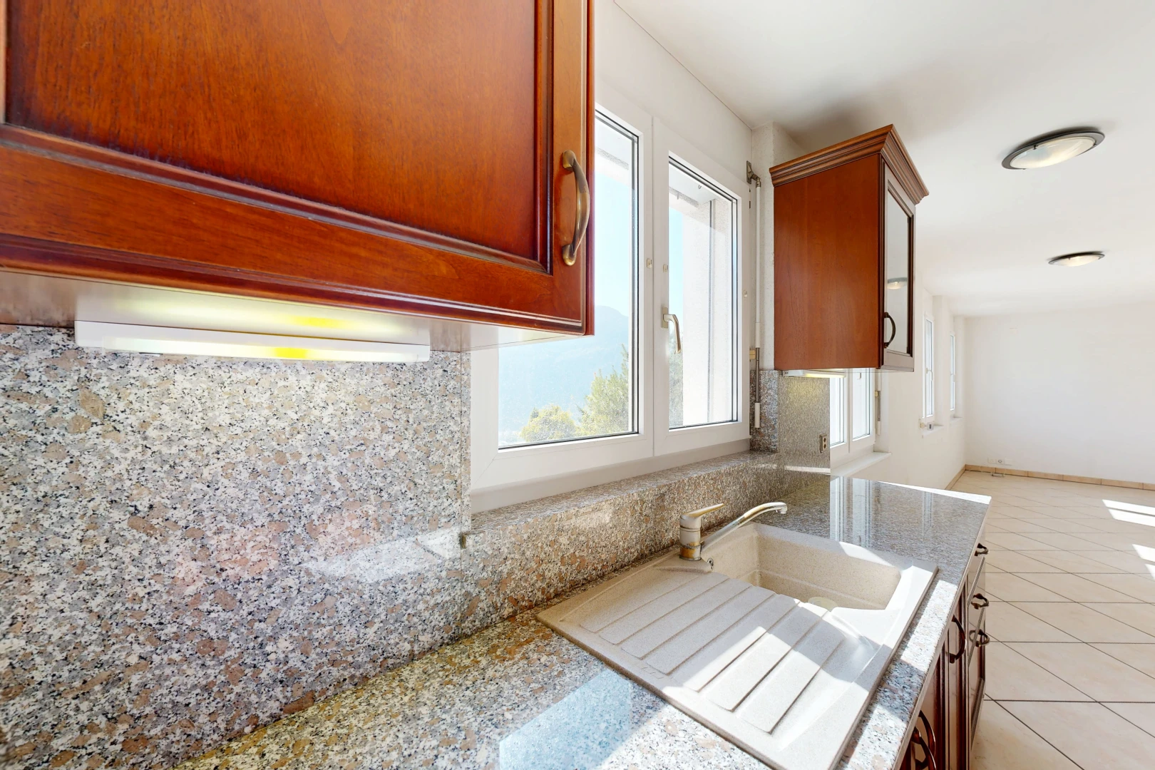 cuisine avec light floor, armoires avec moulures, crown molding cabinets, light countertops, et armoires marron moyen