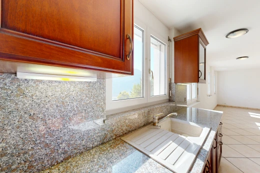 cuisine avec light floor, armoires avec moulures, crown molding cabinets, light countertops, et armoires marron moyen