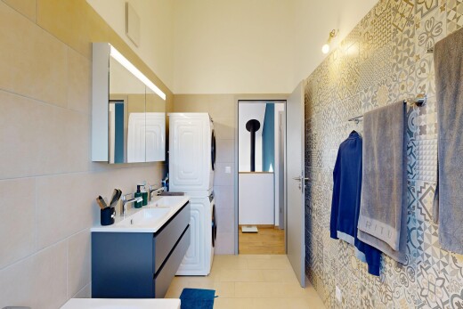 salle de bains avec mur en carrelage, tile wall, double vasque, miroir, et light floor