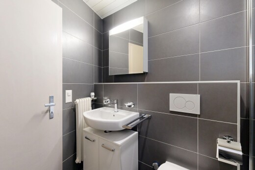 salle de bains avec mur en carrelage, tile wall, miroir, lavabo (ou coiffeuse selon le contexte), et radiateur
