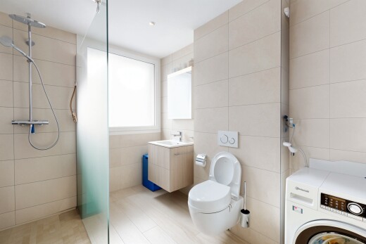 full bathroom with washer / clothes dryer, tile walls, a tile shower, toilet, and vanity