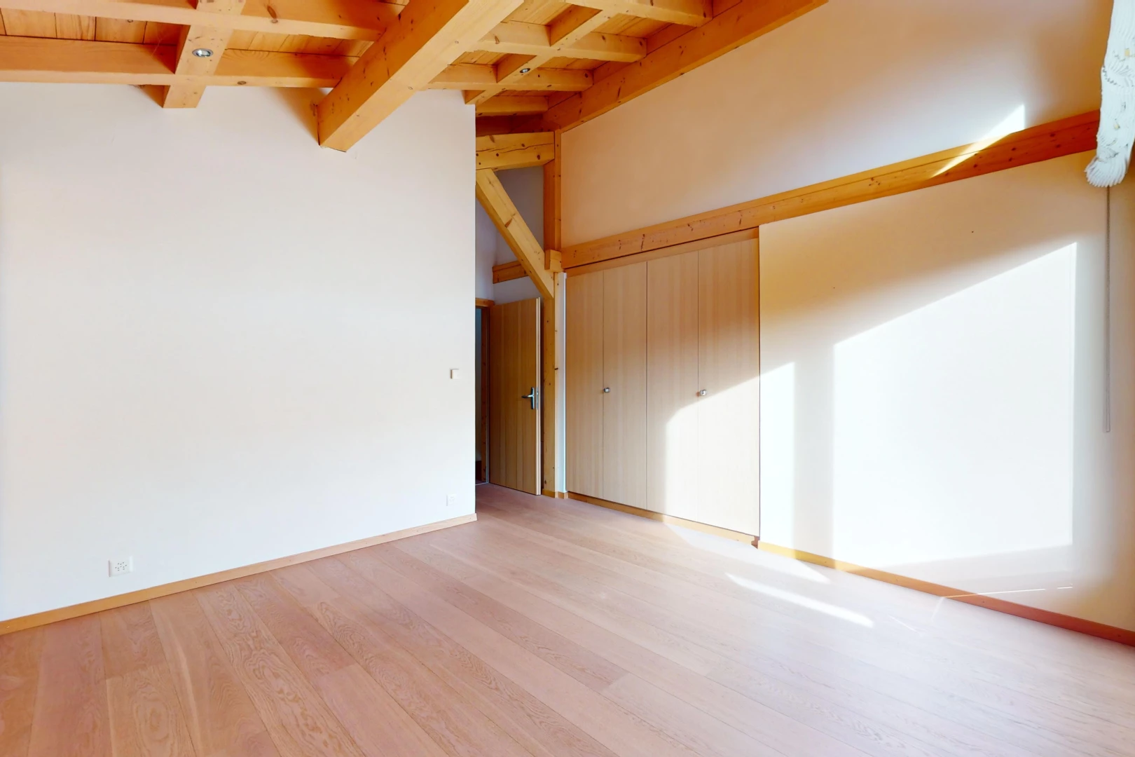 empty room with light wood-type flooring and beam ceiling