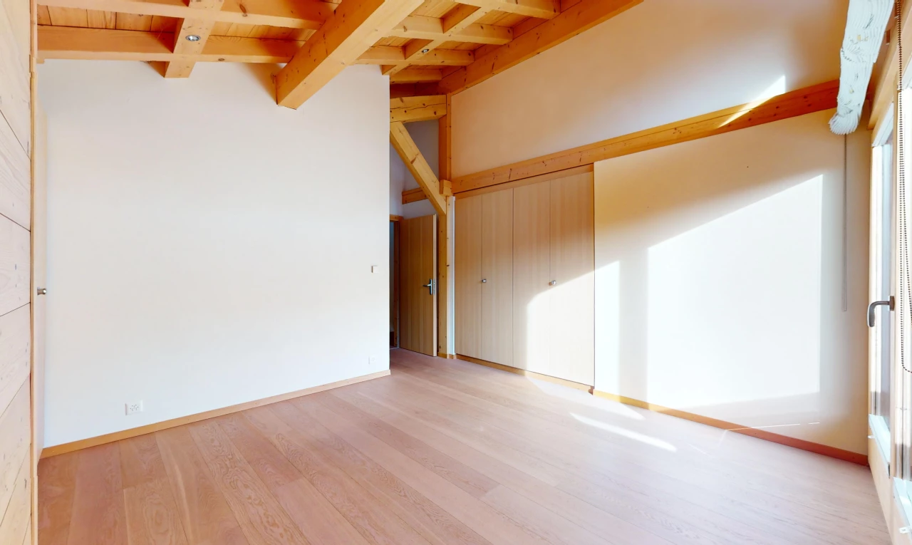 empty room with light wood-type flooring and beam ceiling