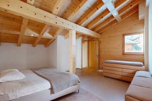 chambre avec poutres apparentes, plafond de bois, plafond voûté, lumière naturelle, et mur en bois