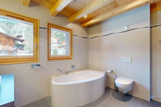 salle de bain avec poutres apparentes, toilettes, baignoire, lumière naturelle, et carrelage
