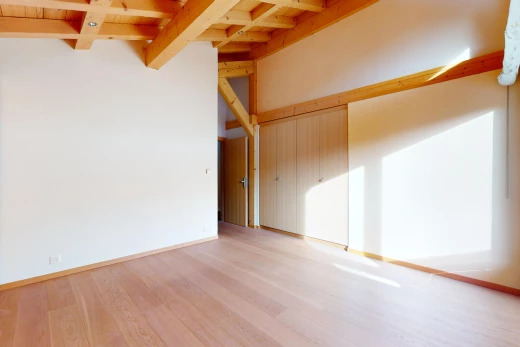 empty room with light wood-type flooring and beam ceiling