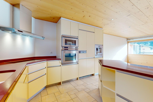 cuisine avec carrelage, plafond de bois, lumière naturelle, hotte, et four double