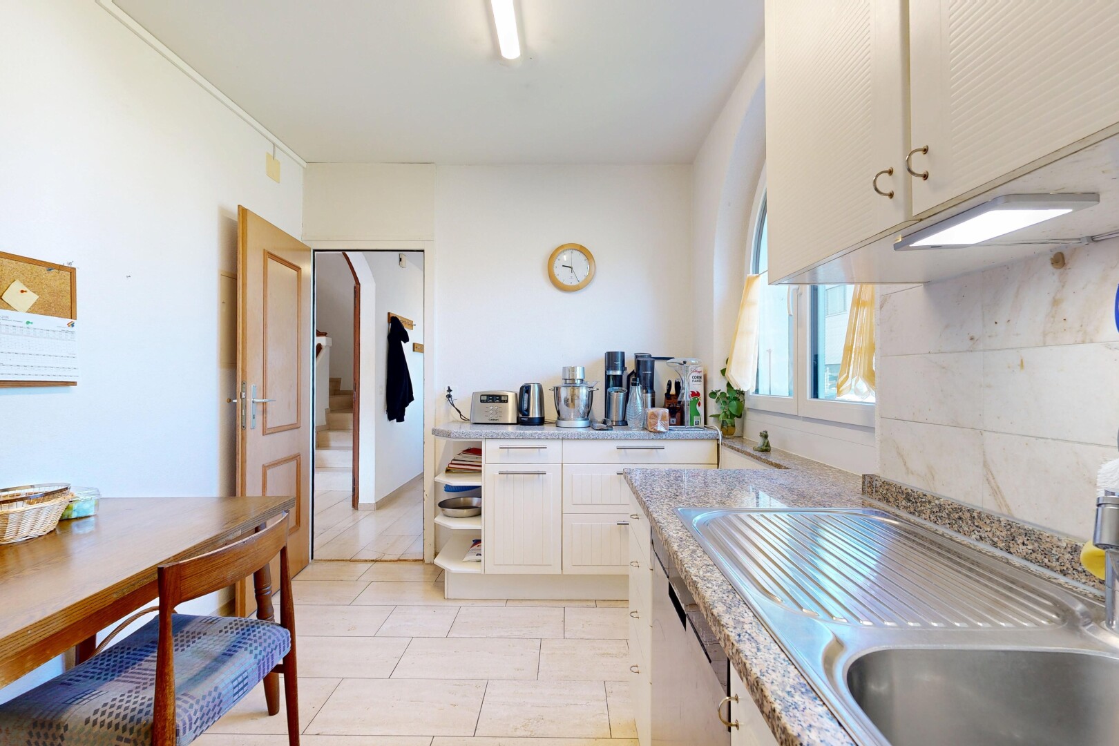 cuisine avec armoires blanches, white cabinets, light countertops, évier, et light floor