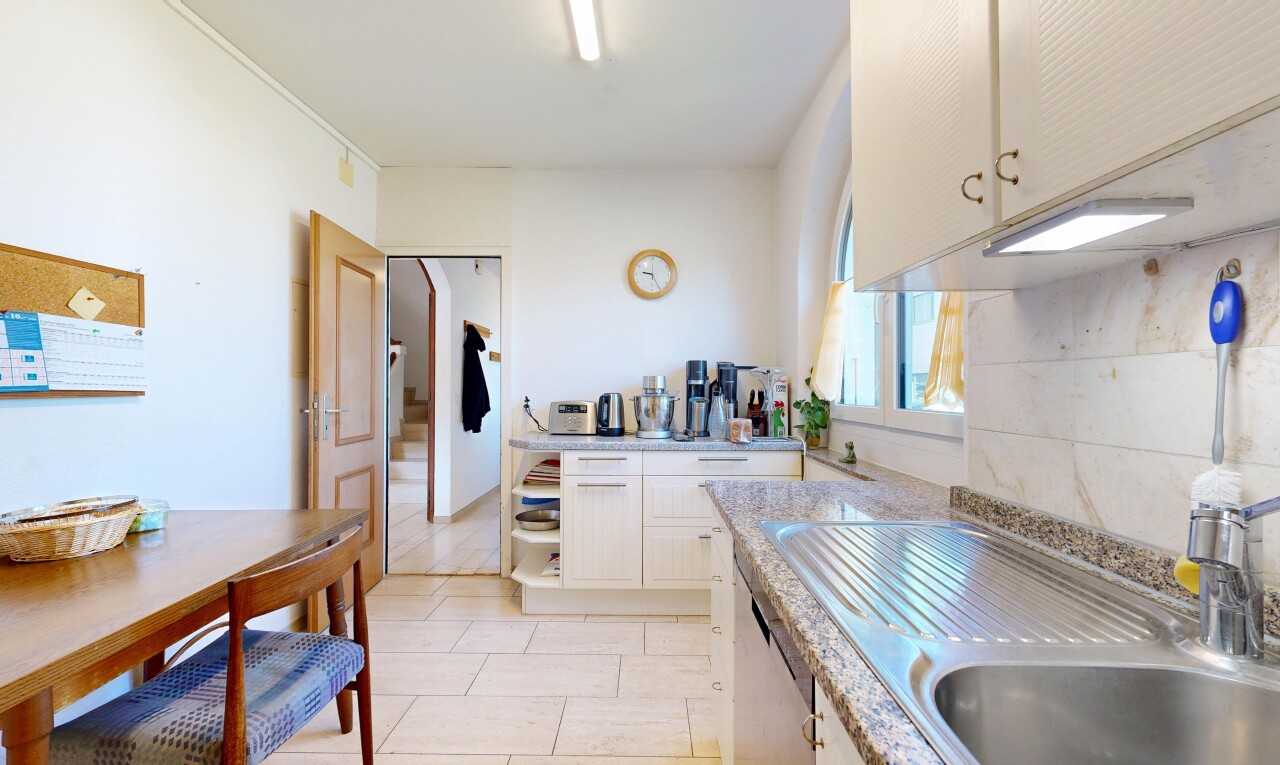 cuisine avec armoires blanches, white cabinets, light countertops, évier, et light floor