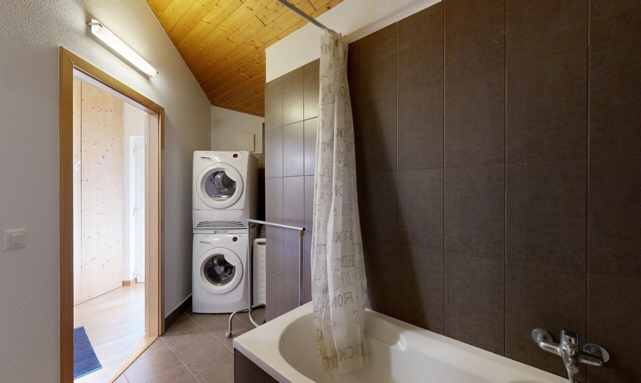 buanderie avec buanderie, lave-linge et sèche-linge superposés, wood ceiling, plafond en bois, et tile floor