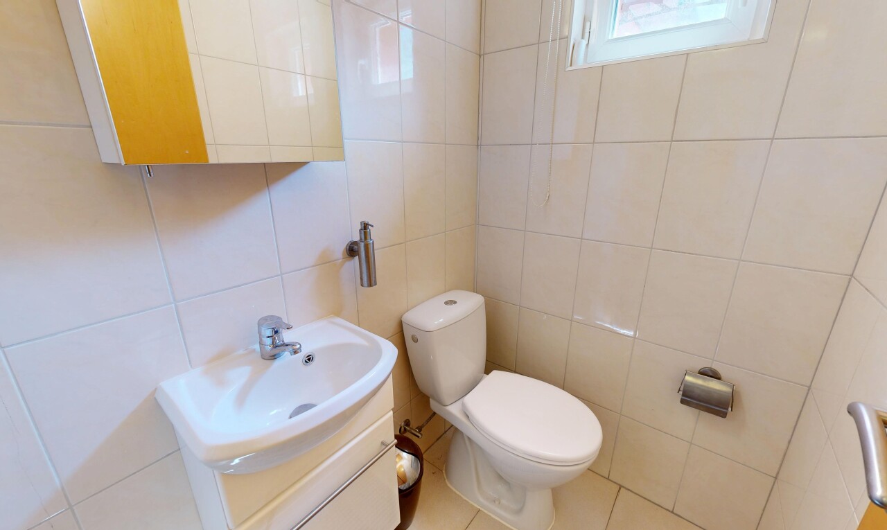 salle de bains avec tile wall, mur en carrelage, miroir, toilette, et lavabo (ou coiffeuse selon le contexte)