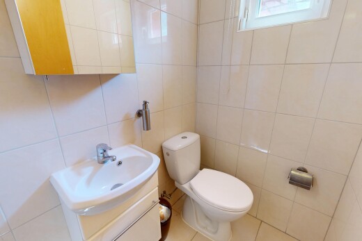 salle de bains avec tile wall, mur en carrelage, miroir, toilette, et lavabo (ou coiffeuse selon le contexte)