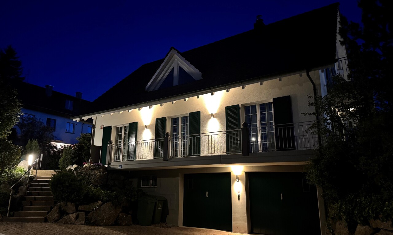 façade avec night time, balcon, garage intégré, allée, et escaliers