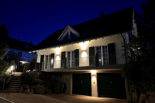 façade avec night time, balcon, garage intégré, allée, et escaliers
