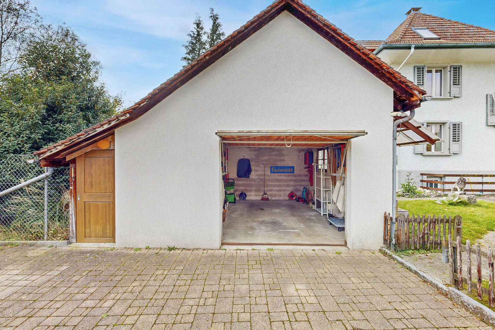 façade avec clôture, bardage en stuc, property visible, terrasse, et garage attaché