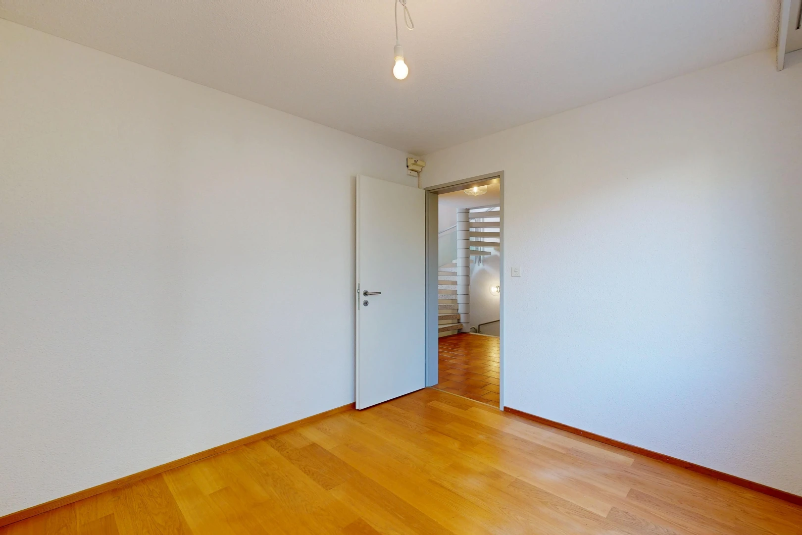 pièce vide avec wood finish floor, sol en finition bois, drywall, cloison sèche, et escaliers