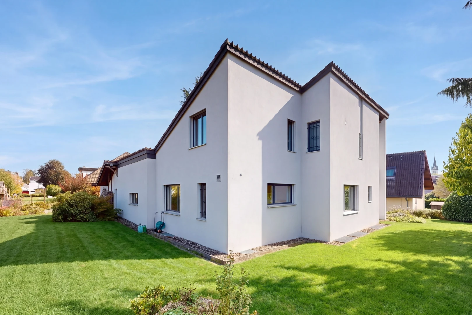 façade avec pelouse, bardage en stuc, property visible, toit en tuiles, et day time