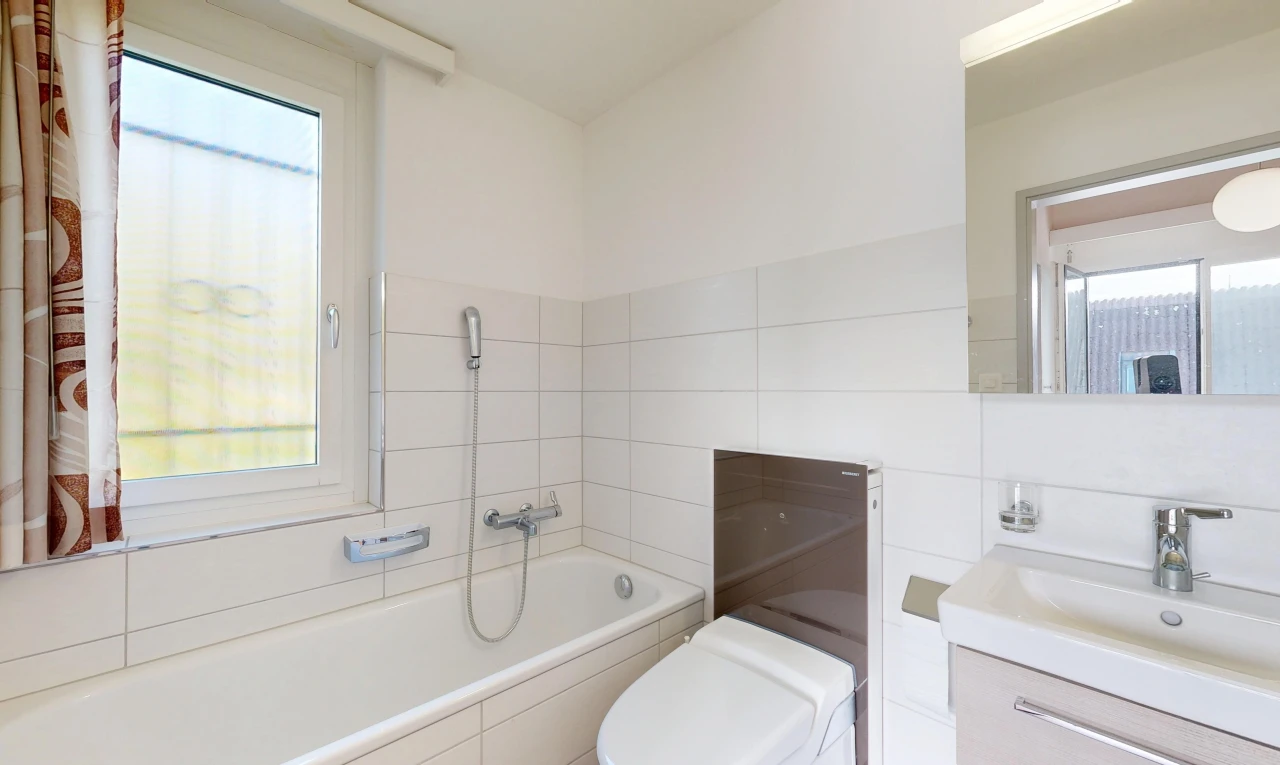 salle de bains avec bain, salle de bain complète, miroir, lavabo (ou coiffeuse selon le contexte), et toilette