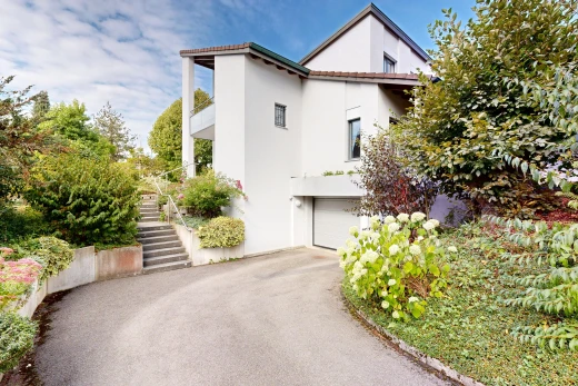 façade avec escaliers, bardage en stuc, garage intégré, allée, et property visible