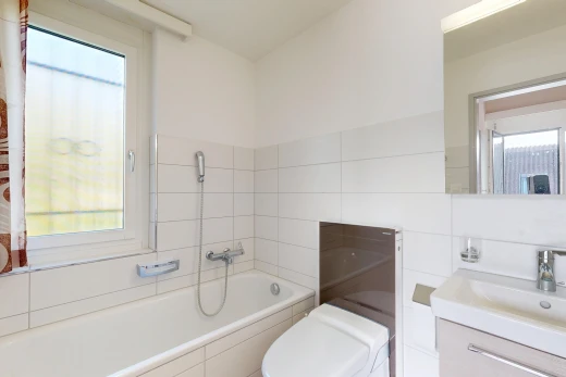 salle de bains avec bain, salle de bain complète, miroir, lavabo (ou coiffeuse selon le contexte), et toilette