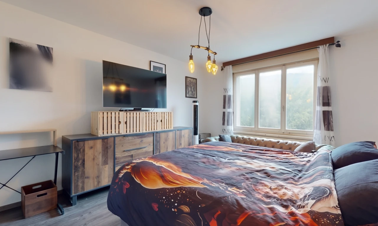 chambre avec télévision, cloison sèche, drywall, sol en finition bois, et wood finish floor