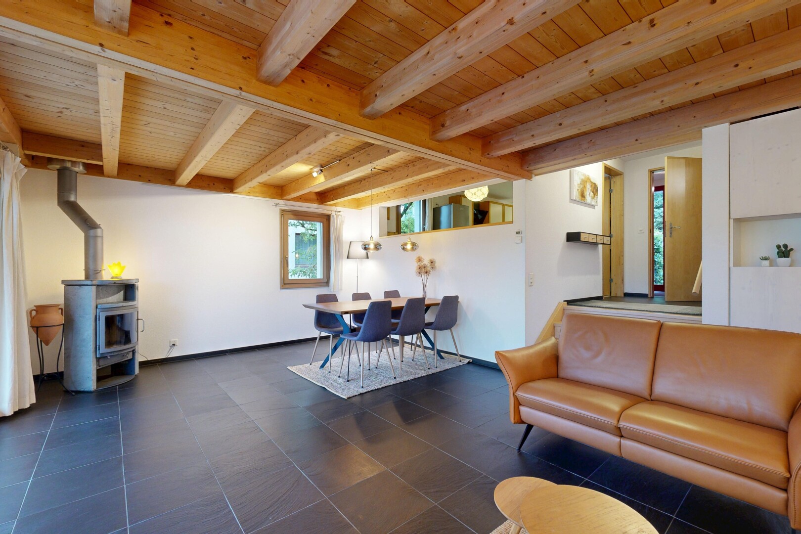 wohn- / esszimmer mit holzofen, inside community, gipskartonwand, drywall, und balkendecke