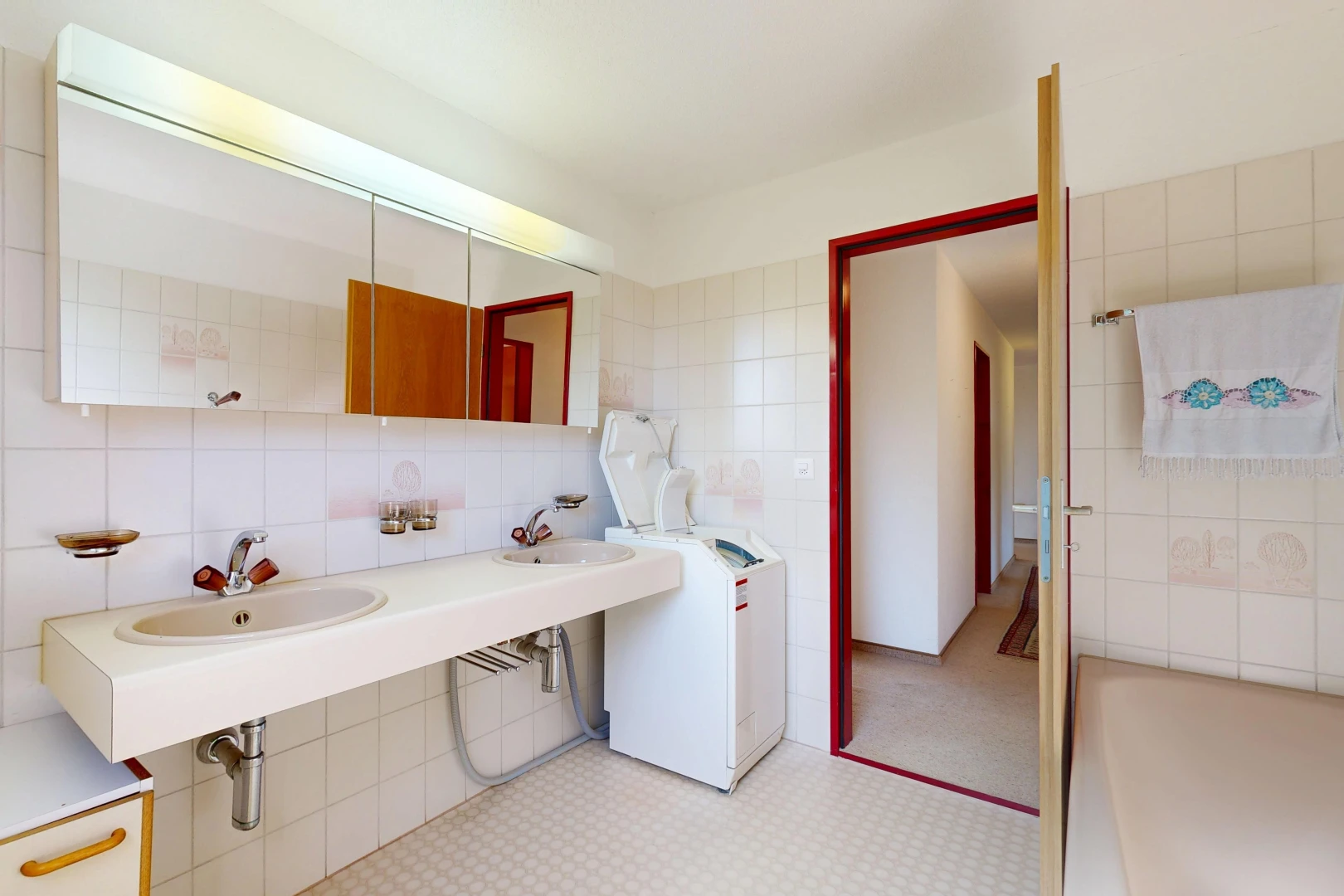 salle de bains avec miroir, tile wall, mur en carrelage, light floor, et évier
