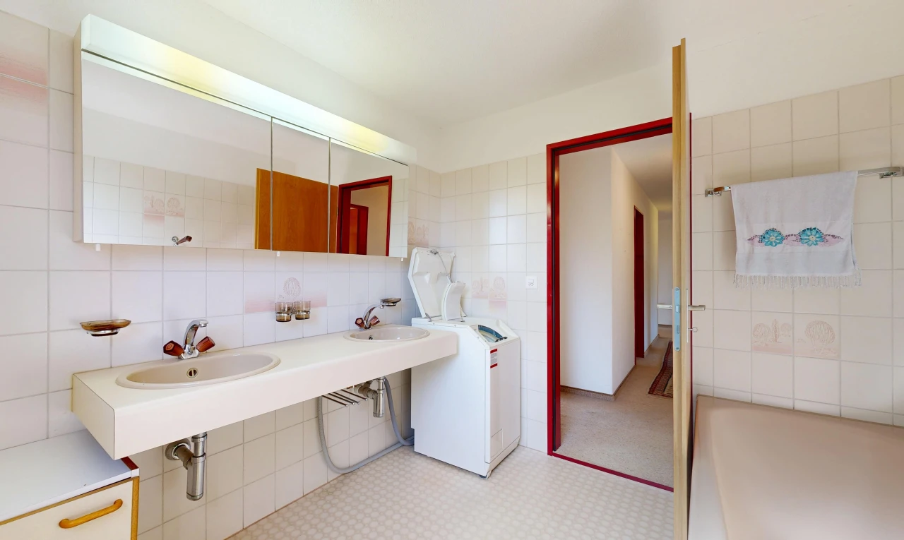 salle de bains avec miroir, tile wall, mur en carrelage, light floor, et évier