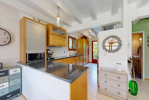 kitchen featuring beam ceiling, wood finish cabinetry, hanging light fixtures, a peninsula, and dark stone counters