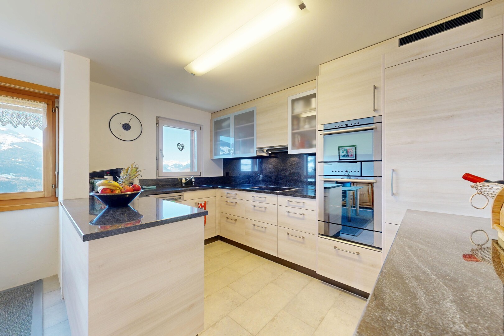 cuisine avec péninsule de cuisine, kitchen peninsula, armoires avec insert en verre, glass insert cabinets, et dark countertops