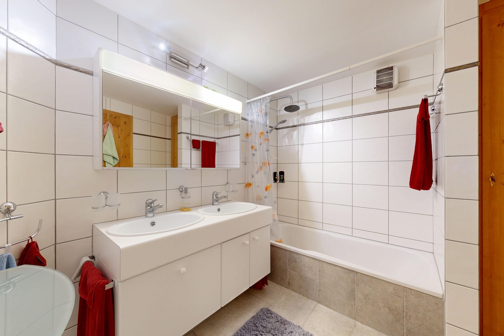 salle de bains avec douche-bain combinés, double vasque, tile wall, mur en carrelage, et miroir