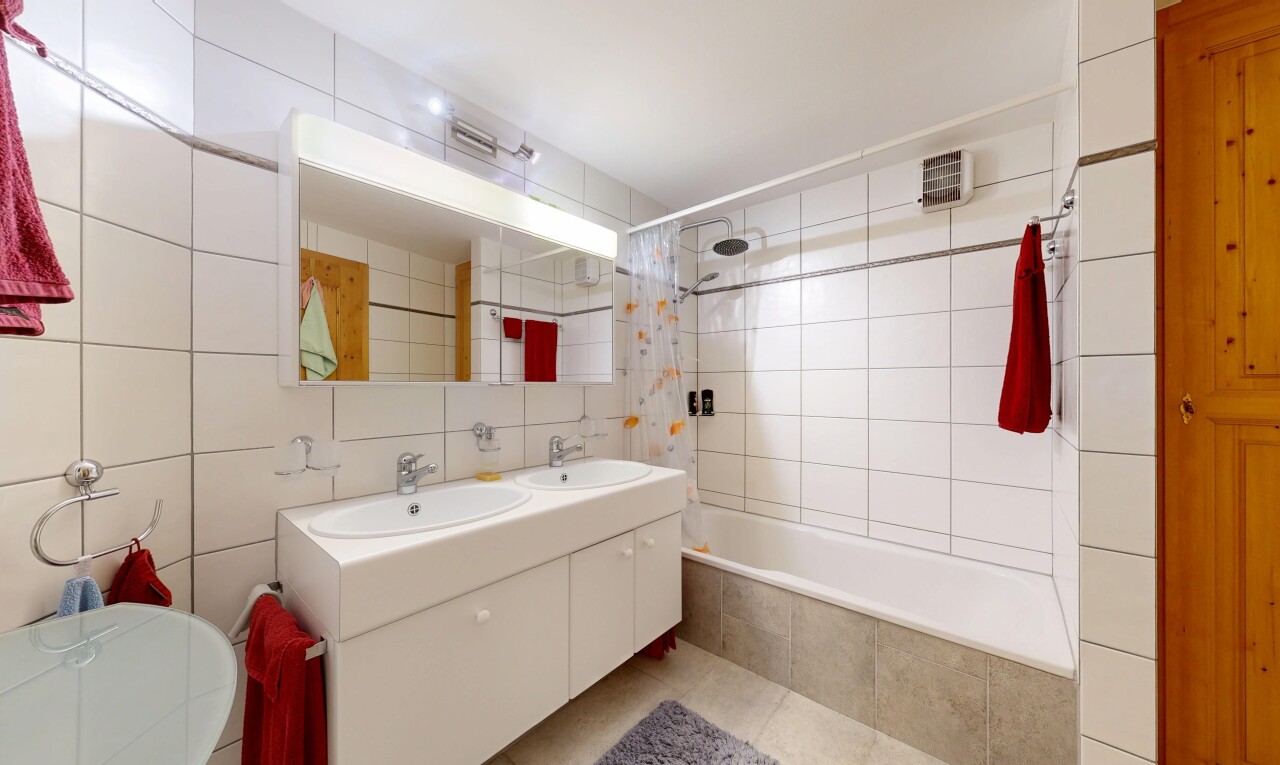 salle de bains avec douche-bain combinés, double vasque, tile wall, mur en carrelage, et miroir