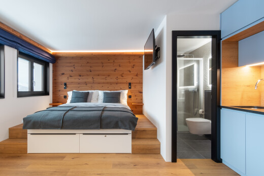 room / bedroom with light wood finished floors, ensuite bathroom, and wooden walls