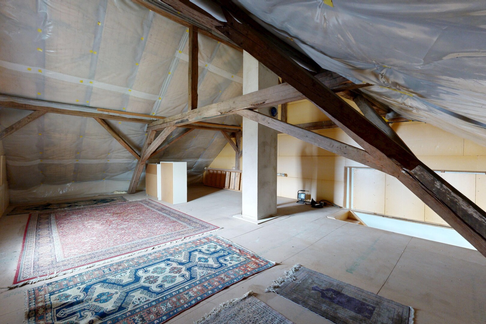 pièce vide avec unfinished floor, inside property, plafond voûté, et vaulted ceiling