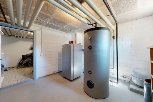 interior space featuring water heater, concrete block wall, and concrete floors